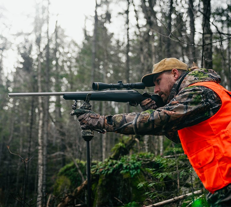 Chasseur en tenue camouflage vise dans la forêt.