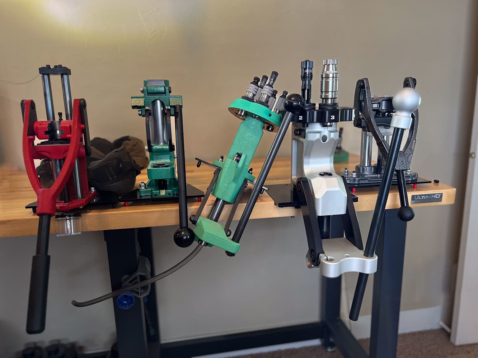 Un banc de rechargement bien organisé avec plusieurs presses manuelles à un étage pour le rechargement des munitions, démontrant différents modèles et configurations